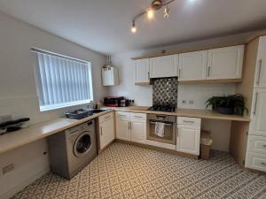 a kitchen with white cabinets and a washing machine at Stay @ Enville Close, Birmingham Airport & NEC in Marston Green