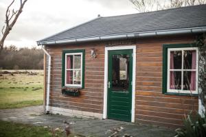 杜廷赫姆的住宿－Groepsaccommodatie - De Ooymanhoeve，一座带绿门和两扇窗户的小房子