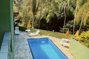 a swimming pool with chairs and umbrellas in a yard at Chácara Paraíso in Mairiporã