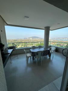 a table and chairs in a room with a view at Vista Panorâmica Enseada in Guarujá