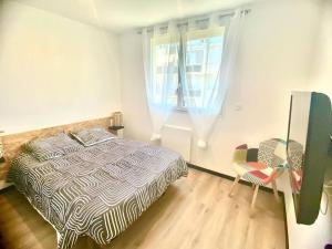 a bedroom with a bed and a table and a window at *Superbe appartement moderne* in Lourdes