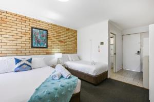 圖翁巴的住宿－格倫沃思汽車旅館，一间卧室设有两张床和砖墙