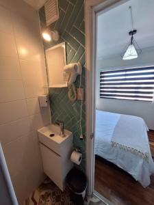 baño pequeño con lavabo y cama en Hostal Terraza Recreo, en Viña del Mar