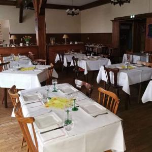 una sala da pranzo con tavoli e sedie bianchi di Hôtel restaurant à la croix d'or a Sessenheim