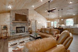 ein Wohnzimmer mit Ledermöbeln und einem Steinkamin in der Unterkunft Luxe Mineral Bluff Vacation Rental with Game Room! in Mineral Bluff