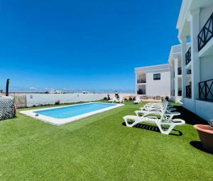 a yard with chairs and a swimming pool and the beach at Ola Cotillo Beach El Cotillo in El Cotillo