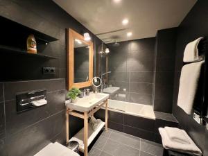 a black bathroom with a sink and a bath tub at Luxury Alpine Residence with Hot Tub - By Ski Chalet Andorra in Soldeu