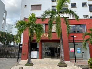 un bâtiment rouge avec des palmiers devant lui dans l'établissement Magico Apartamento con Piscina 1 Habitación PR65, à Montería