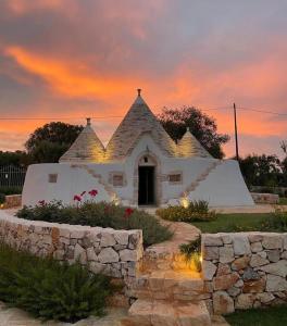 un pequeño edificio blanco con una puesta de sol en el fondo en Trullo il Gatto Nero, en Ostuni