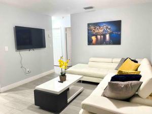 uma sala de estar com um sofá branco e uma televisão em GREAT LOCATION Downtown/Airport/South Beach em Miami
