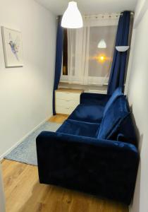 a living room with a blue couch and a window at Ursus Rooms-Self Check-in in Warsaw