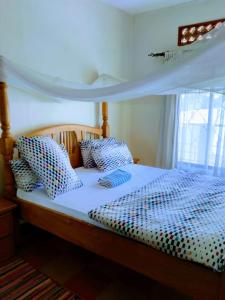 a bed with blue and white pillows on it at Kampala Ntinda Comfy Holiday Home in Kampala