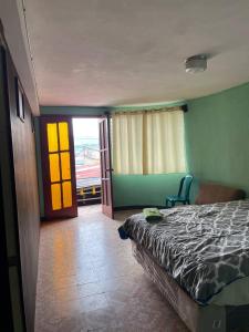 een slaapkamer met een bed en een deur naar een balkon bij Casa Julia Xela in Quetzaltenango