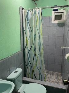 y baño con cortina de ducha y aseo. en Casa Julia Xela en Quetzaltenango