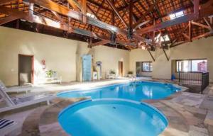 a large pool with blue water in a building at Apartamento Duplex Alto do Capivari in Campos do Jordão