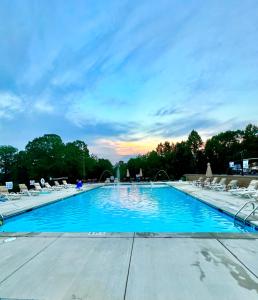 a large swimming pool with chairs and a sunset at Broad River Campground Cabins & Domes in Boiling Springs