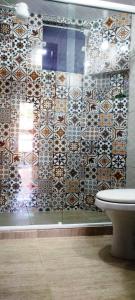 a bathroom with a toilet and a tiled wall at Casa Verde da Floresta da Gávea in Visconde De Maua