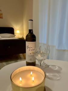 a bottle of wine and glasses on a table with a candle at Venetian Gem Central Corfu Retreat in Kanoni