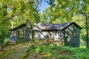 a green house with a porch in the woods at Pinnacle Mountain Falls Sunset Cottage with Deck in Sunset