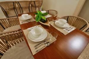 een tafel met stoelen en een houten tafel met borden en borden bij Casa Belcher in Cozumel