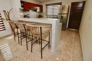 eine Küche mit einer Bar mit Stühlen und einem Kühlschrank in der Unterkunft Casa Belcher in Cozumel