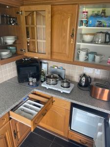 a kitchen with wooden cabinets and a stove with pots and pans at Music of the Sea- Isle of South Uist, HS8 5RF in Clachan