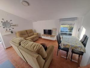 een woonkamer met een bank en een tafel met stoelen bij BertoaLand Relax y Diversión Apartamento de 2 dormitorios dobles con terraza privada y zona de juegos compartida in Carballo