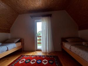 an attic room with two beds and a window at Vila Paramida in Šavnik