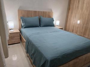 a bedroom with a bed with blue sheets and two lamps at شقة جميلة وهادئة in Agadir