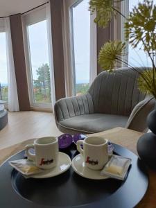 dos tazas y platillos en una mesa en una sala de estar en WEST Panorama Penthouse - apartment with a fantastic view of the city, en Szombathely
