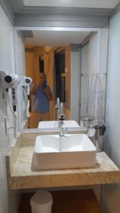 un hombre tomando una foto de un lavabo en un baño en Flat Caldas Novas, en Caldas Novas
