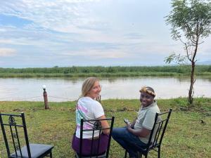 にあるSemliki Fishing River Campの川の椅子に座る男女