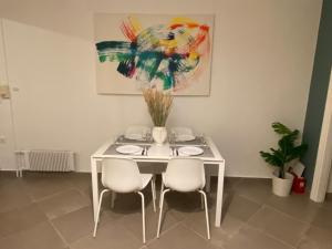 雅典的住宿－Glyfada apartment near the Center，一张带椅子的白色桌子和墙上的一幅画