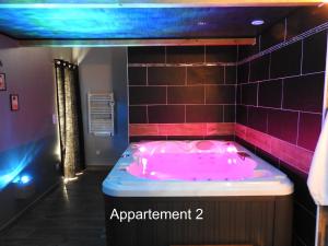 La salle de bains est pourvue d'une baignoire rose et de carrelage violet. dans l'établissement Love Room Narbonne, à Narbonne