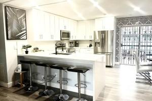 a kitchen with white cabinets and a large island with bar stools at SUPER CLOSE Beach, Airport, port, Downtown, Wynwood in Miami