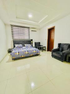 a bedroom with a bed and a couch and chairs at Beautiful new 4 bed townhouse in Lagos