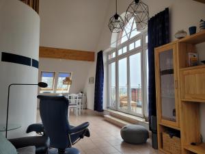 a living room with a chair and a large window at SUNSET LOFT Rerik Meerblick Maisonettewohnung mit großem Balkon in Rerik