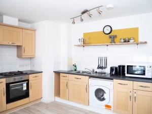 a kitchen with a washing machine and a microwave at Stylish 2 bedroom apartment in the heart of Epsom town centre in Epsom