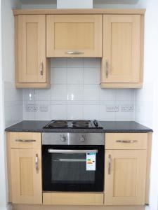 a kitchen with a stove and wooden cabinets at Stylish 2 bedroom apartment in the heart of Epsom town centre in Epsom