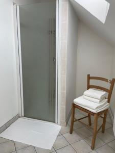 a shower with a chair and a glass shower stall at Les Epicuries de la ferme Ecolodge 