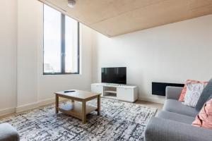 ein Wohnzimmer mit einem Sofa und einem TV in der Unterkunft Two Bedrooms Exquisite En-Suite Apartment Deansgate in Manchester