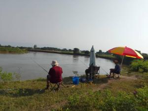 的住宿－Semliki Fishing River Camp，坐在一把伞下椅子上的两个人