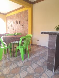 een eetkamer met groene stoelen en een stenen muur bij Hospedaje Matita - Torotoro in Torotoro