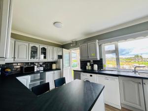 a kitchen with white cabinets and a black counter top at Ocean View House -Connemarra in Galway