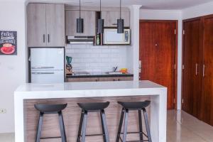 a kitchen with a white counter and two bar stools at Suite 806 extraordinaria vista al rio con piscina. in Guayaquil