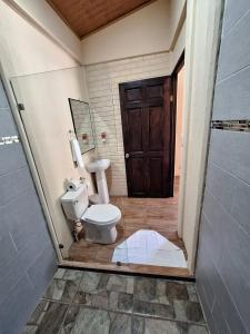 a bathroom with a toilet and a wooden door at The Secret Eco Lodge in Tortuguero