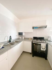 een keuken met witte kasten en een zwarte oven bij Oasis Punta Cana Apartments 3 in Punta Cana