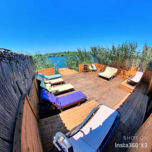 a deck with chaises and chairs on it next to the water at Ada Bojana Green in Ulcinj