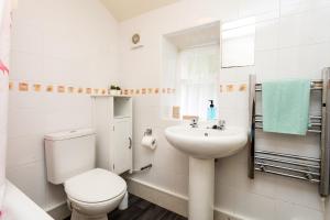 a white bathroom with a toilet and a sink at Bilton Farm Cottage No2 in Alnmouth +22 photos