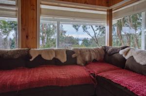a couch with blankets on it in front of a window at Cabaña puerto varas, a orillas del Lago LLanquihue in Puerto Varas
